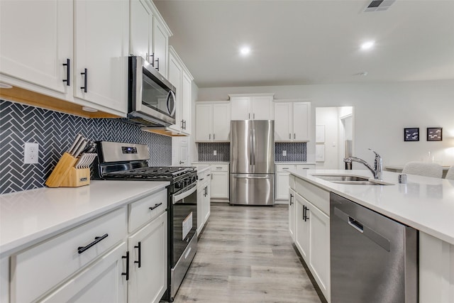 kitchen with sink, white cabinets, light wood-type flooring, and appliances with stainless steel finishes