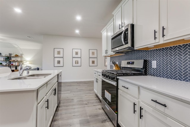 kitchen featuring sink, stainless steel appliances, light hardwood / wood-style flooring, backsplash, and white cabinets