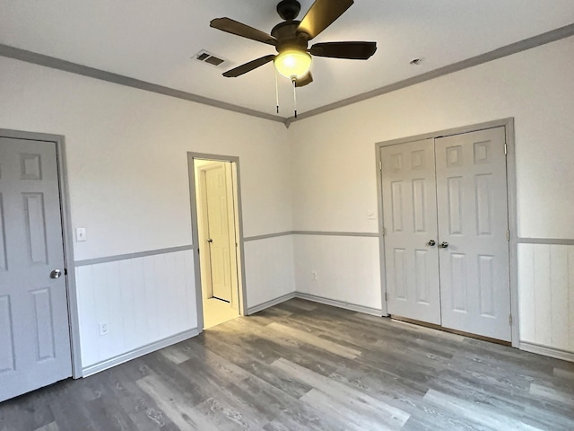 unfurnished bedroom with ceiling fan, ornamental molding, hardwood / wood-style floors, and a closet