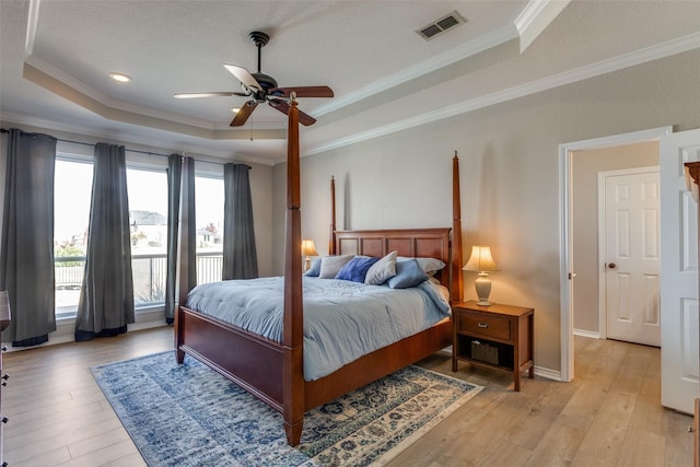 bedroom featuring ceiling fan, ornamental molding, multiple windows, and a tray ceiling