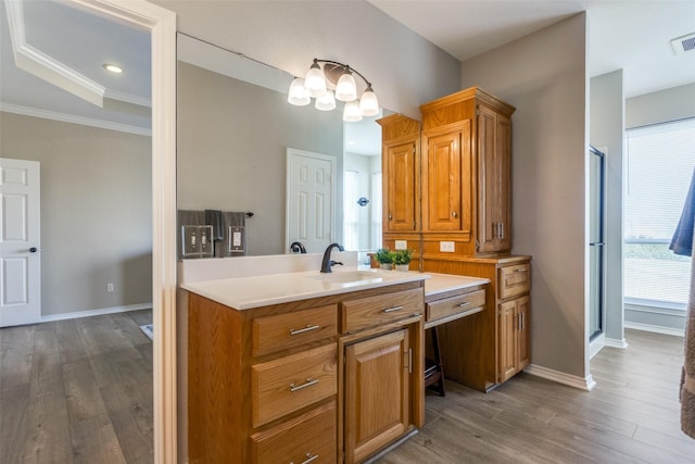 kitchen with a raised ceiling, crown molding, sink, and hardwood / wood-style flooring