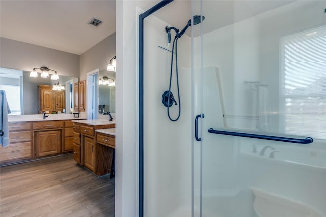 bathroom featuring hardwood / wood-style floors, vanity, a healthy amount of sunlight, and a shower with door