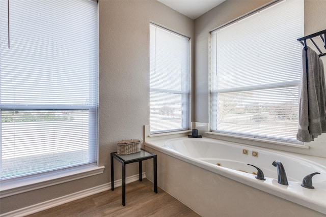 bathroom featuring a tub, a healthy amount of sunlight, and hardwood / wood-style flooring