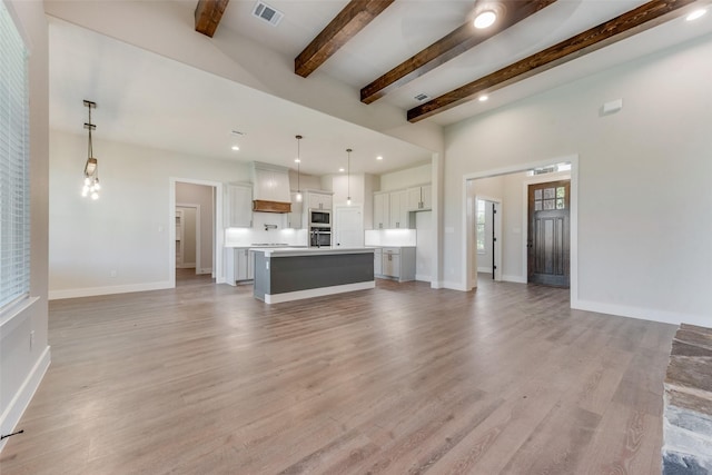 unfurnished living room featuring beam ceiling and light wood-type flooring