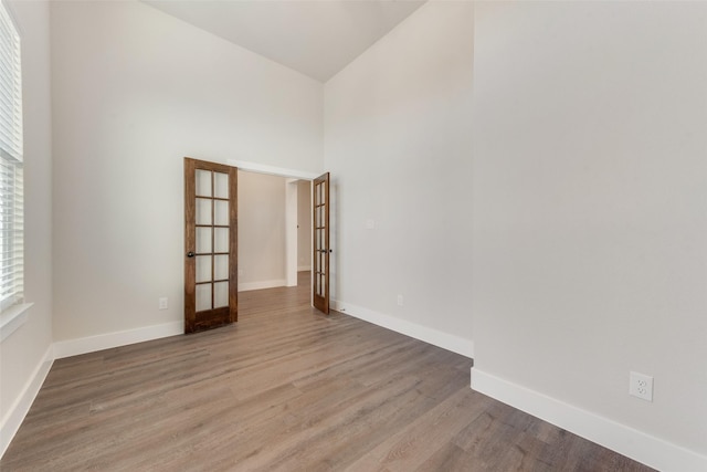 empty room with french doors, hardwood / wood-style floors, and a high ceiling