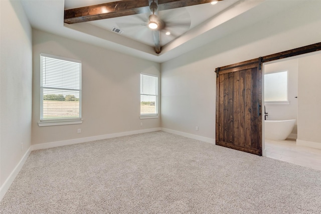 carpeted spare room with a barn door, a raised ceiling, and ceiling fan