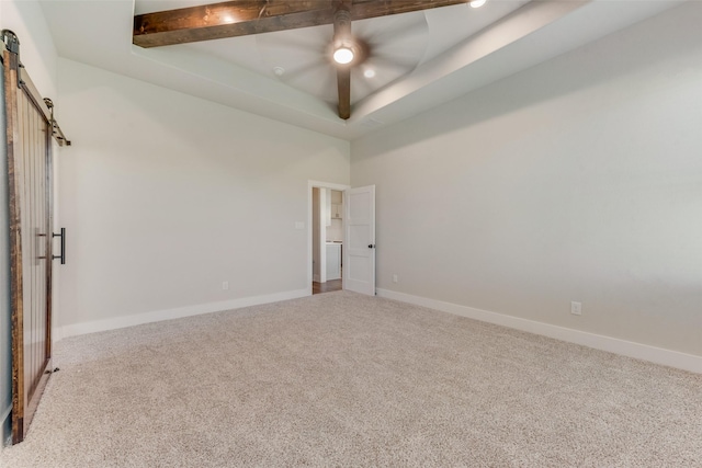 carpeted empty room with ceiling fan, a barn door, and a tray ceiling