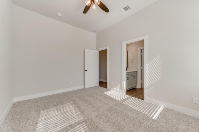 unfurnished bedroom featuring ensuite bath, ceiling fan, and carpet