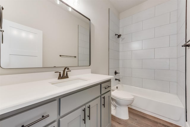 full bathroom with hardwood / wood-style floors, vanity, toilet, and tiled shower / bath