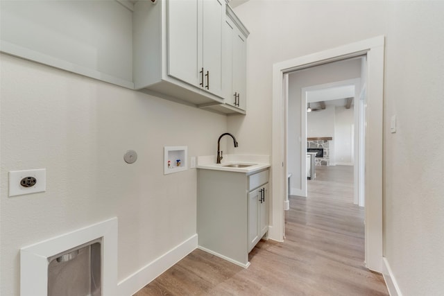 laundry area featuring cabinets, sink, hookup for a washing machine, hookup for an electric dryer, and light hardwood / wood-style floors