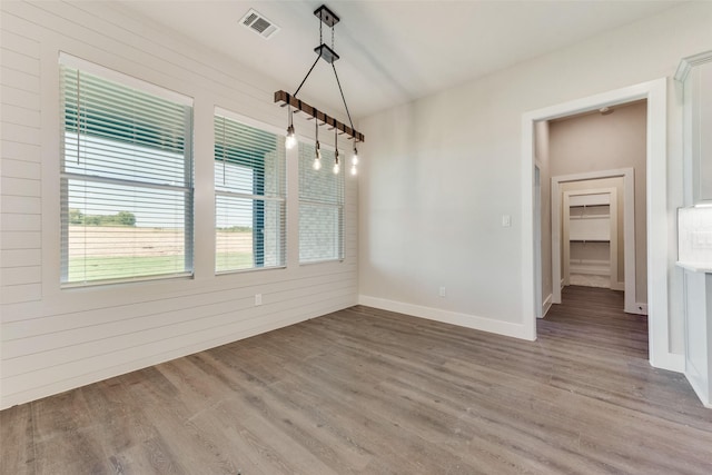 unfurnished dining area with wood walls and light wood-type flooring