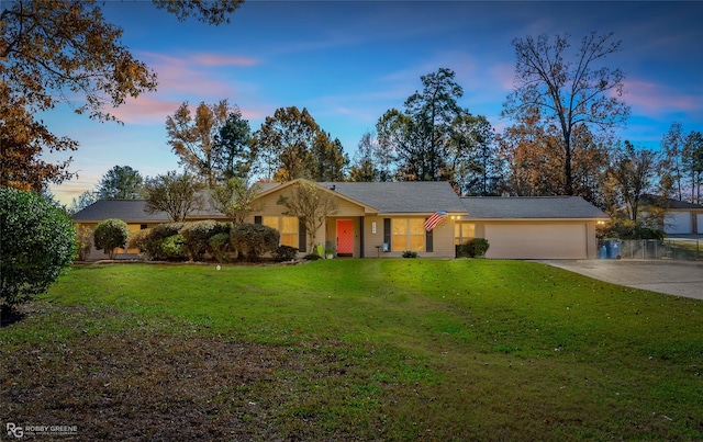 ranch-style home with a garage and a yard