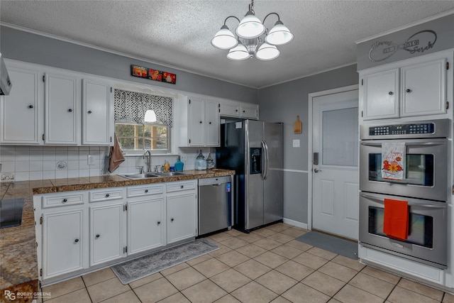 kitchen featuring appliances with stainless steel finishes, white cabinetry, sink, backsplash, and hanging light fixtures