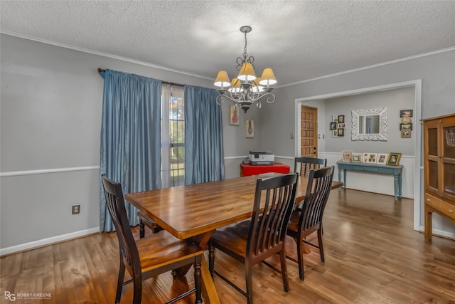 dining area featuring hardwood / wood-style flooring, crown molding, an inviting chandelier, and a textured ceiling