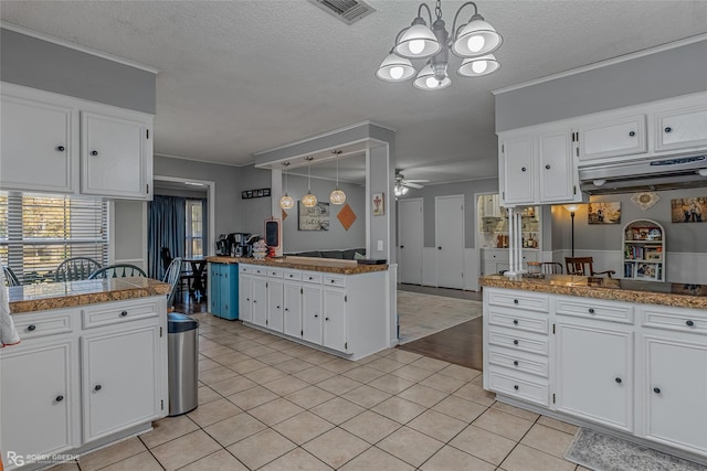 kitchen with hanging light fixtures, light tile patterned floors, kitchen peninsula, and white cabinets