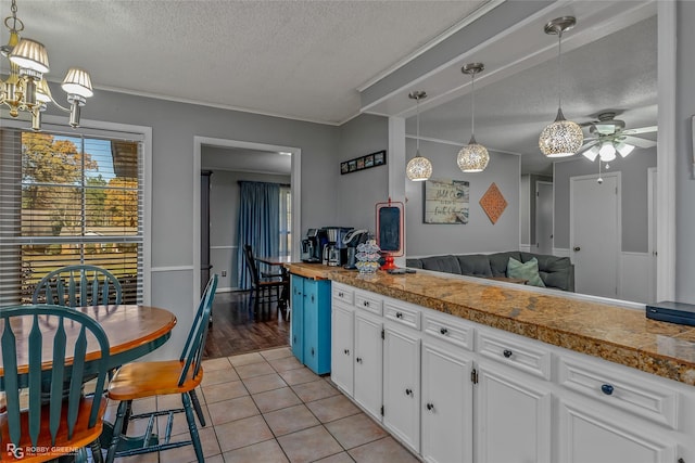 kitchen with white cabinetry, light tile patterned floors, pendant lighting, and a textured ceiling