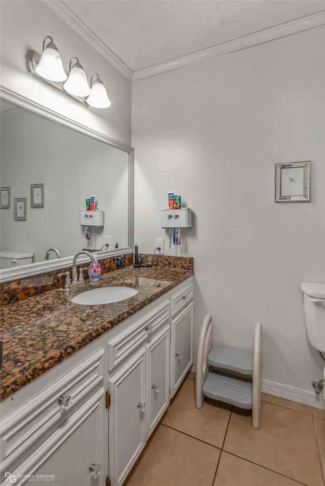 bathroom with tile patterned flooring, ornamental molding, vanity, and toilet