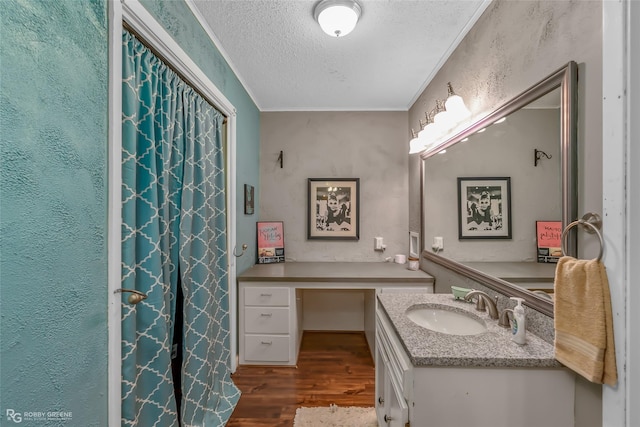 bathroom featuring vanity, hardwood / wood-style flooring, ornamental molding, and a textured ceiling