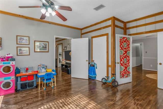 game room with crown molding, washer / dryer, ceiling fan, and dark hardwood / wood-style flooring