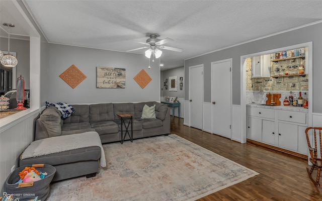 living room with crown molding, a textured ceiling, wood-type flooring, and ceiling fan