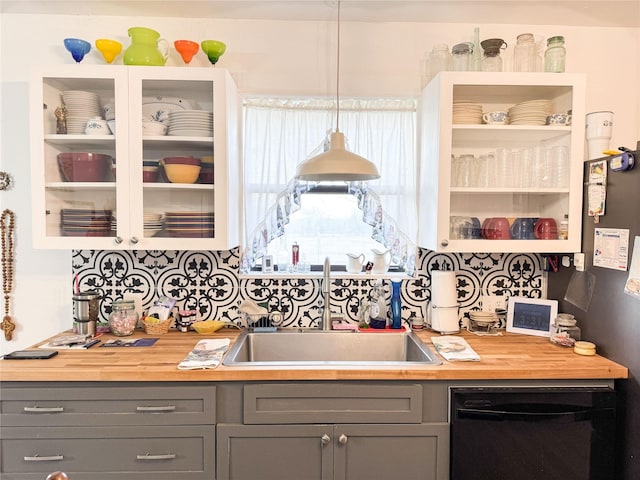 kitchen featuring butcher block countertops, black dishwasher, a sink, and gray cabinetry