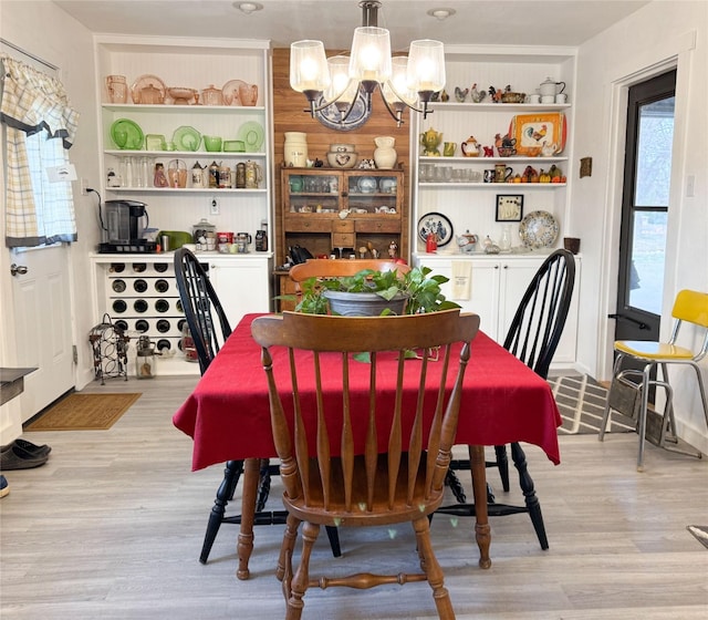 dining room featuring a chandelier, light wood-style floors, and built in features