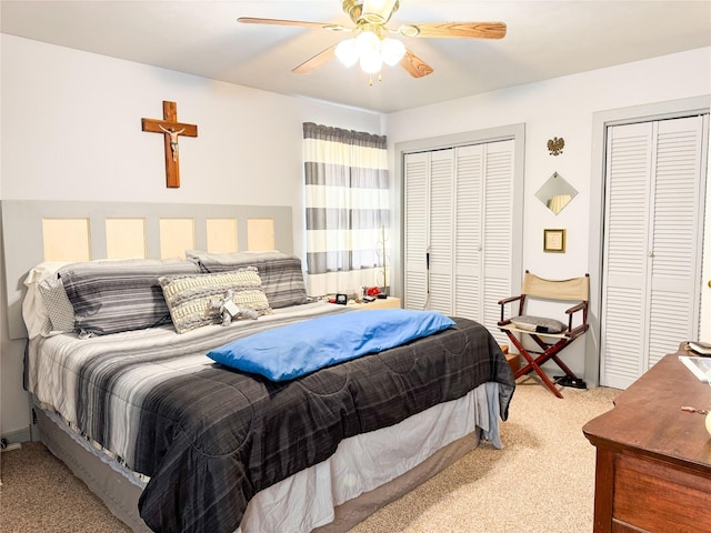 bedroom with a ceiling fan, light carpet, and two closets