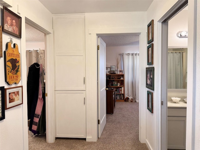 corridor with light carpet and a textured ceiling