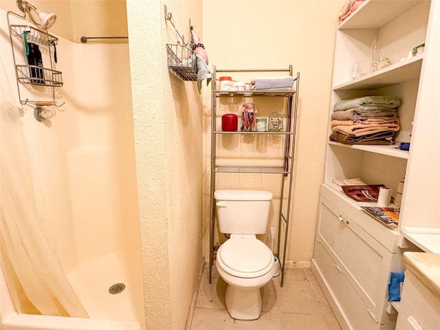 bathroom featuring a shower with shower curtain, tile patterned flooring, and toilet