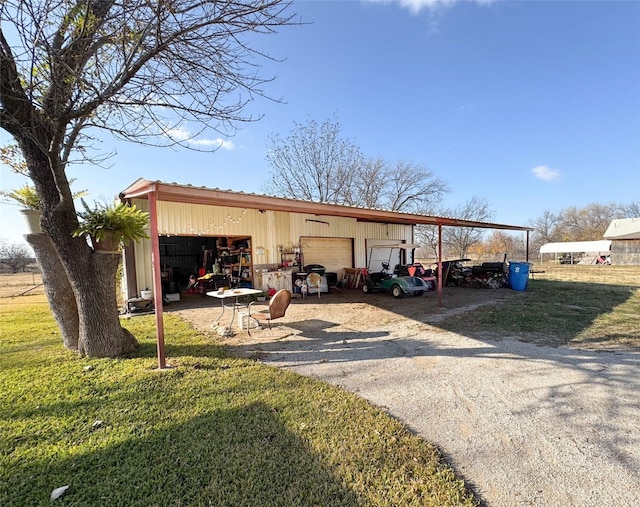 view of outdoor structure featuring a lawn, a carport, and a garage