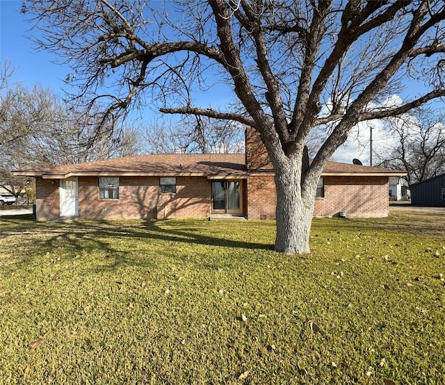 rear view of house featuring brick siding and a yard