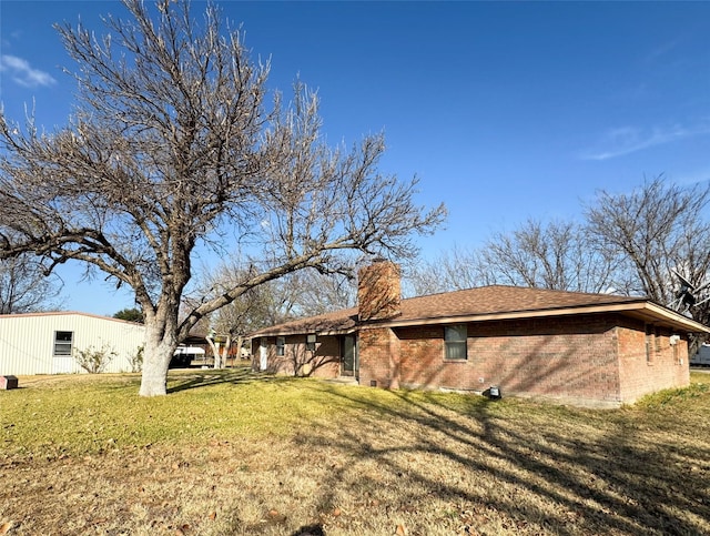 view of side of property featuring brick siding, a yard, and a chimney