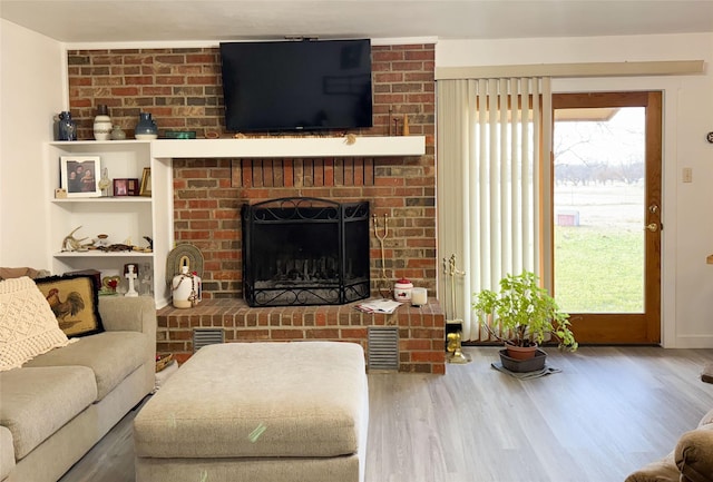 living room featuring a brick fireplace and hardwood / wood-style flooring