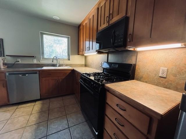 kitchen with light tile patterned floors, black appliances, and sink