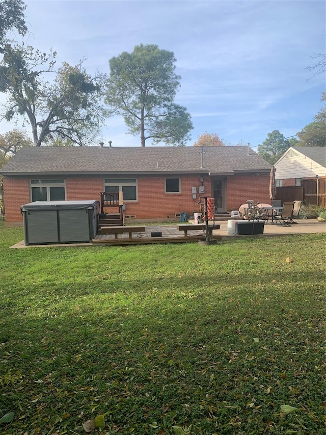 rear view of property with a hot tub, a yard, and a patio area