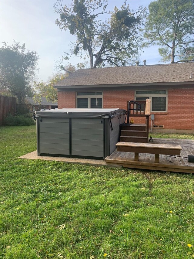 back of property featuring a hot tub, a deck, and a yard