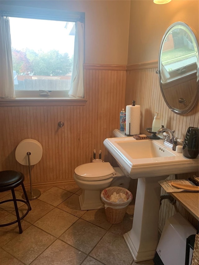 bathroom featuring toilet, wood walls, tile patterned floors, and sink