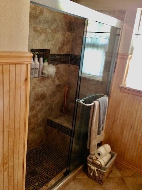 bathroom with a shower with door and tile patterned flooring