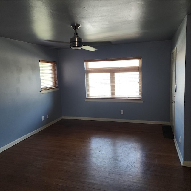 spare room featuring dark hardwood / wood-style flooring, ceiling fan, and a wealth of natural light