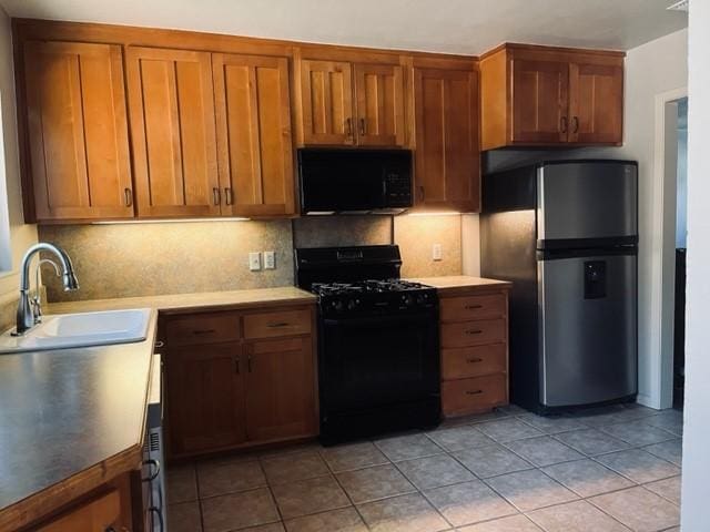 kitchen with black appliances, decorative backsplash, light tile patterned flooring, and sink