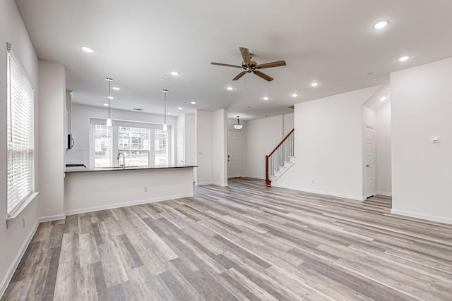 unfurnished living room with sink, light hardwood / wood-style flooring, and ceiling fan