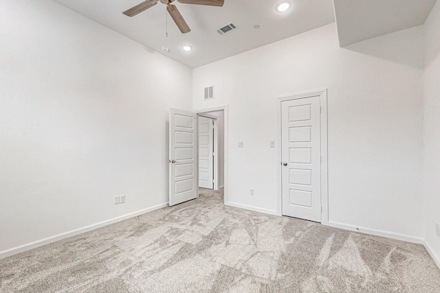 carpeted empty room featuring ceiling fan and a high ceiling