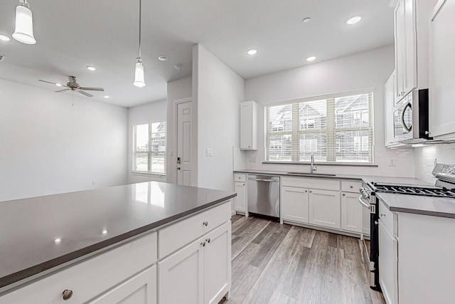 kitchen with hanging light fixtures, sink, white cabinets, and appliances with stainless steel finishes