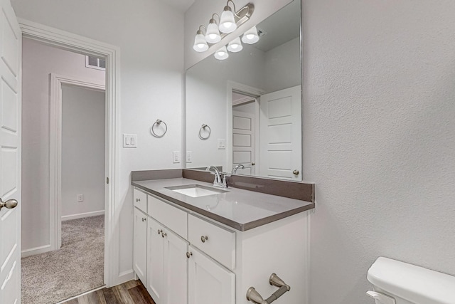 bathroom with vanity, toilet, and hardwood / wood-style floors