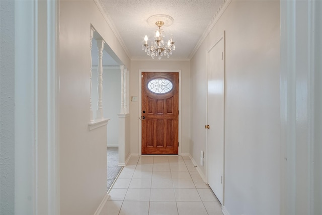 entryway featuring light tile patterned floors, a chandelier, a textured ceiling, and ornamental molding