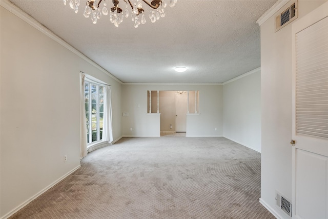 carpeted spare room with ornamental molding, a textured ceiling, and a notable chandelier