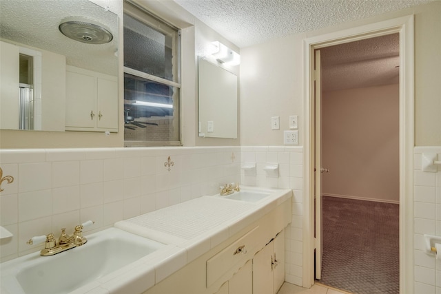 bathroom with vanity, a textured ceiling, and tile walls