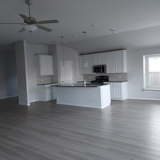 kitchen with white cabinetry, an island with sink, stainless steel appliances, and vaulted ceiling