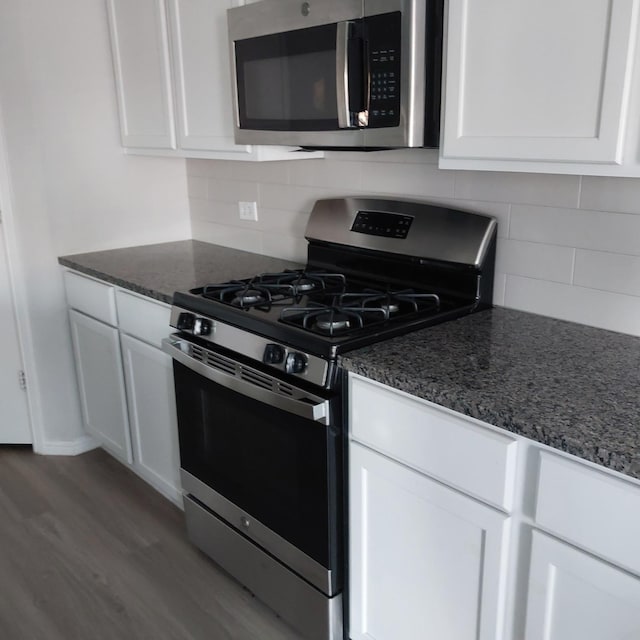 kitchen featuring white cabinets, hardwood / wood-style flooring, decorative backsplash, and appliances with stainless steel finishes