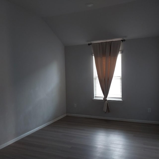 unfurnished room with dark hardwood / wood-style flooring and vaulted ceiling